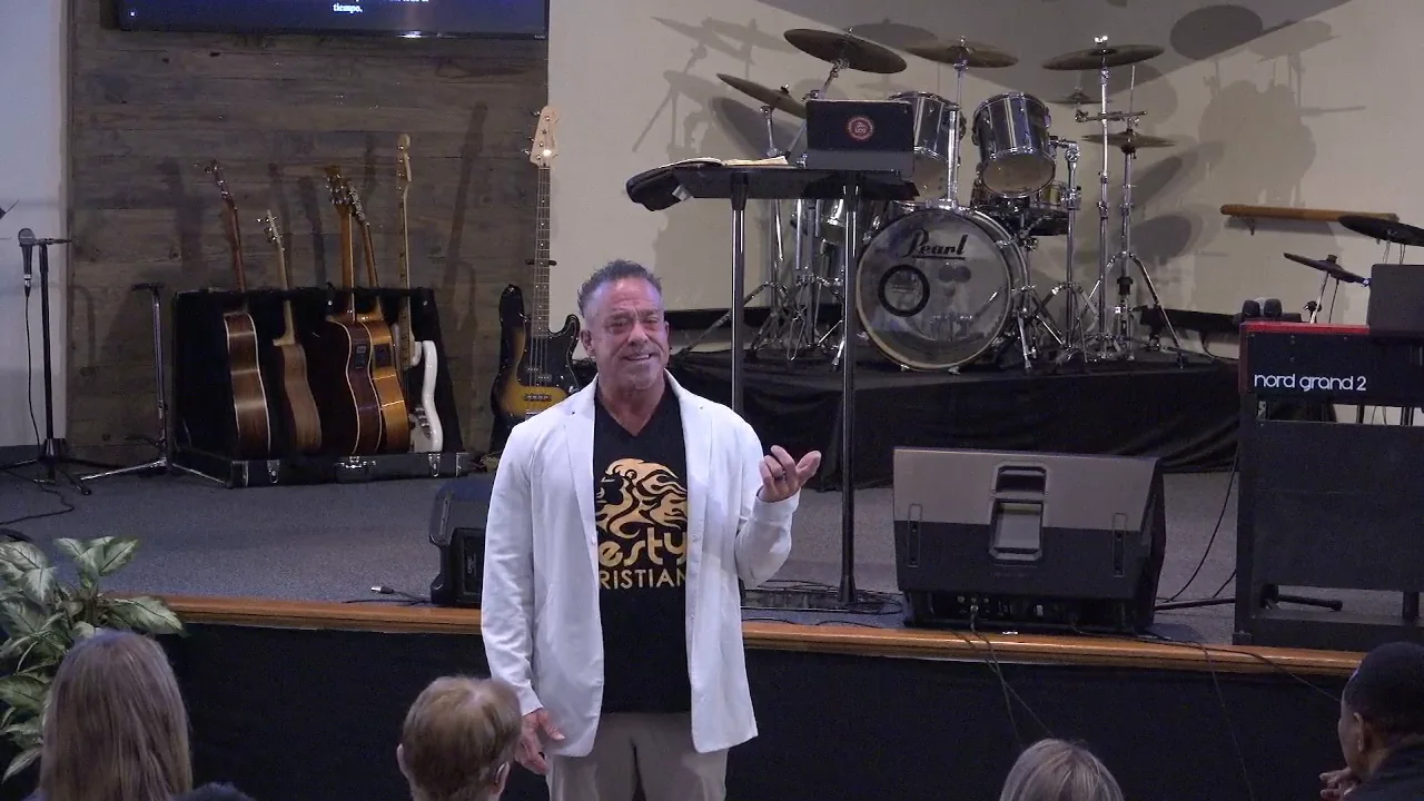 The speaker, arms open and smiling, three seconds into realising the scripture had been on the screens all along.